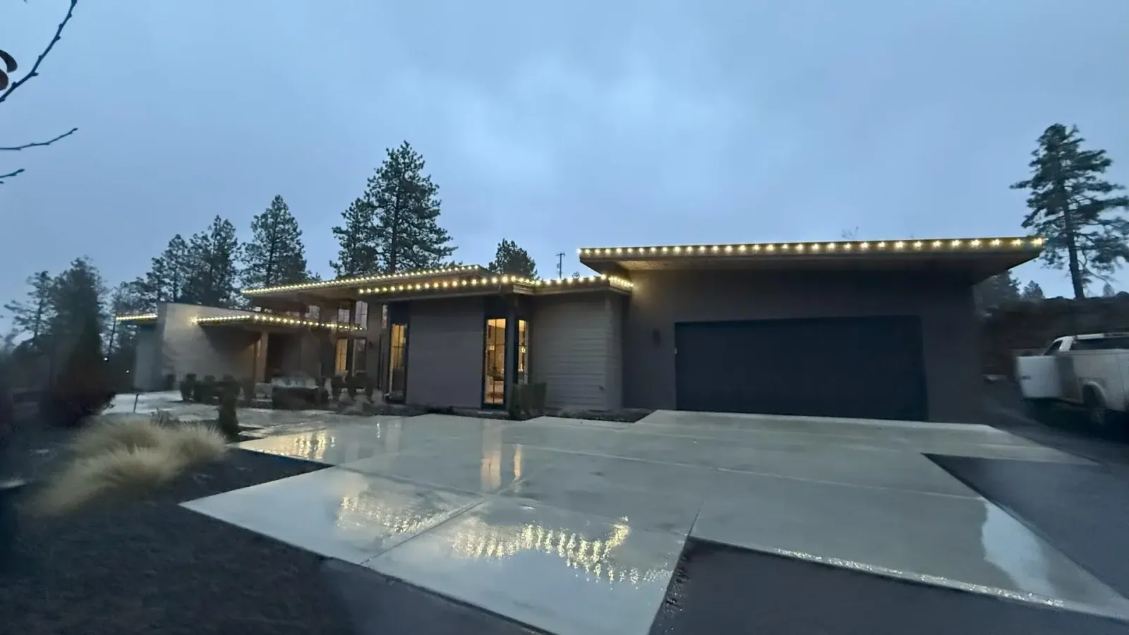 Modern Spokane home with soft white Christmas lights along roofline installed by Greenscape Landscaping.