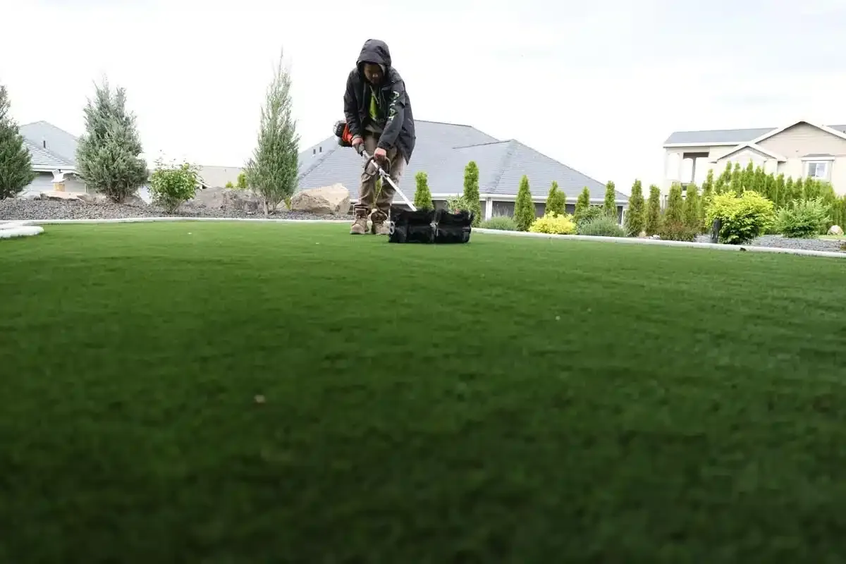 Worker pushing a lawn aerator to perform lawn aeration on a residential lawn